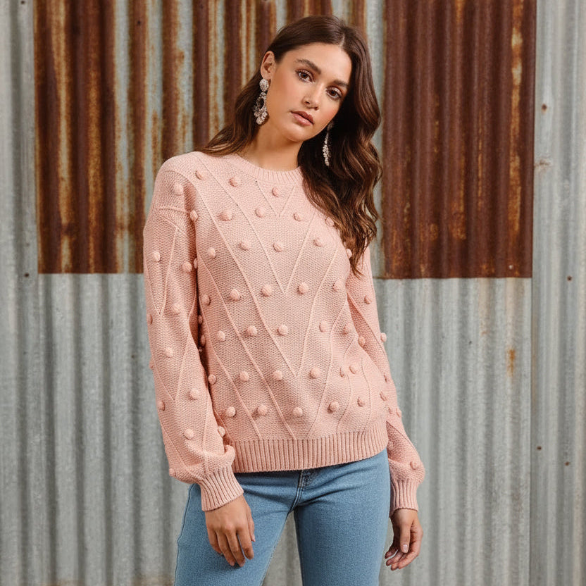 Woman wearing a pink textured sweater against a beige background