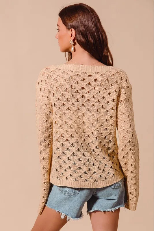 Woman wearing a beige crochet sweater and denim shorts on a beige background