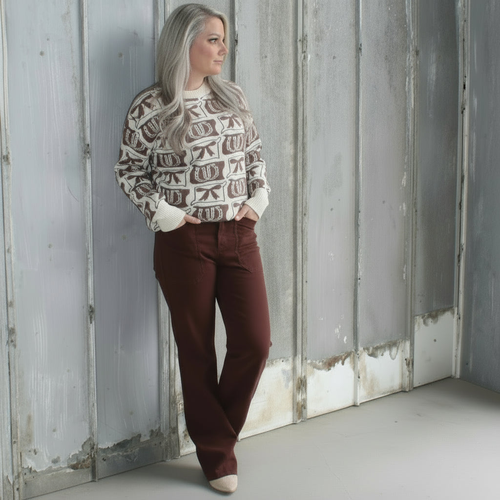 Person standing on a set of concrete steps wearing a patterned sweater and maroon pants.