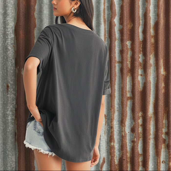 Woman wearing a dark gray oversized t-shirt and denim shorts on a plain background