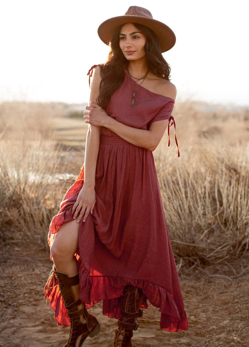 Woman in a red dress and hat standing in a desert landscape