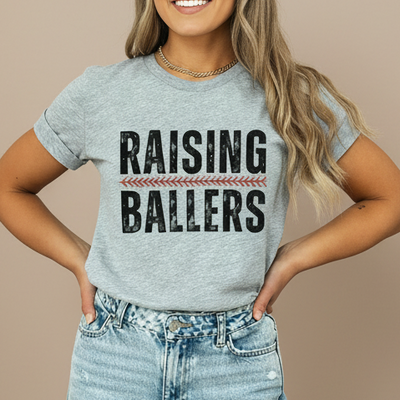 Person wearing a gray t-shirt with 'RAISING BALLERS' text