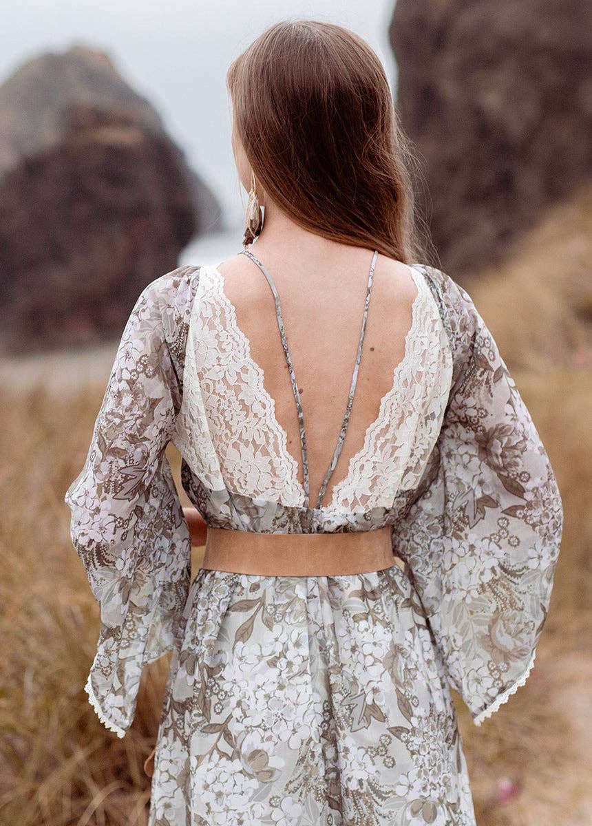 Woman wearing a floral dress with a backless design in a natural setting.