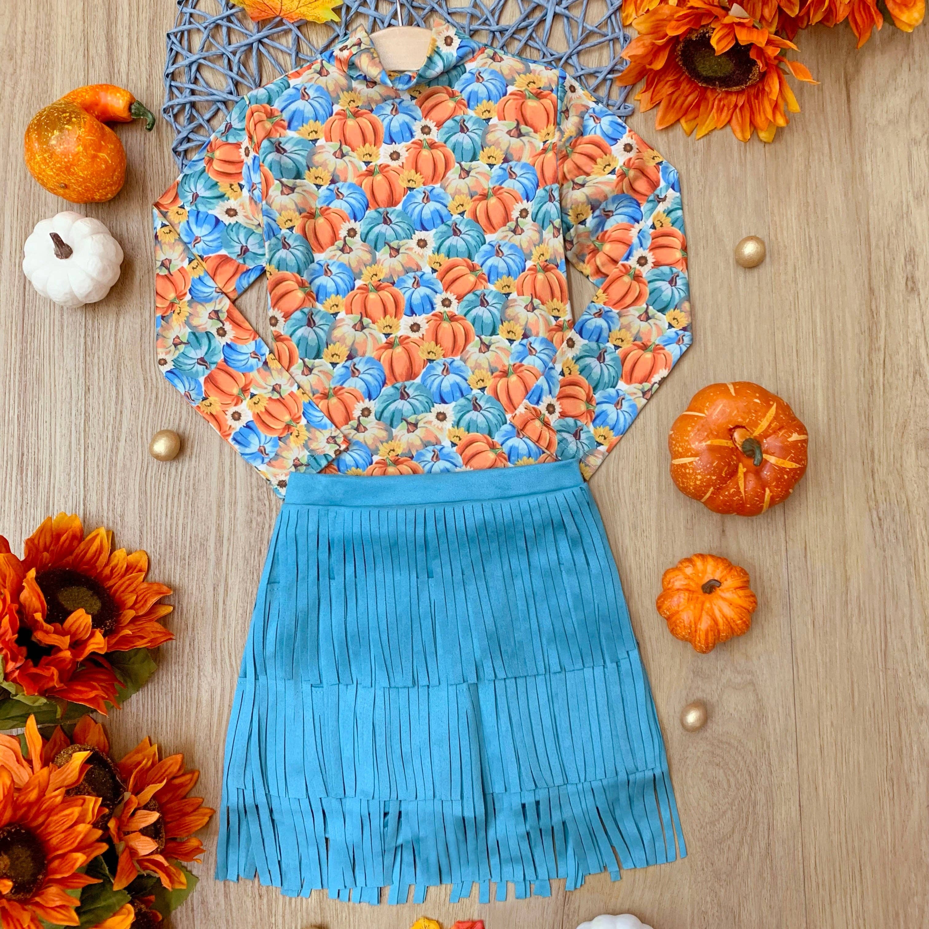 Colorful apron with floral pattern and blue skirt on a wooden surface with autumn decorations.