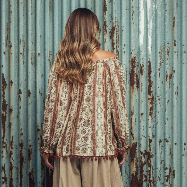 Woman wearing a patterned off-shoulder blouse against a gray background