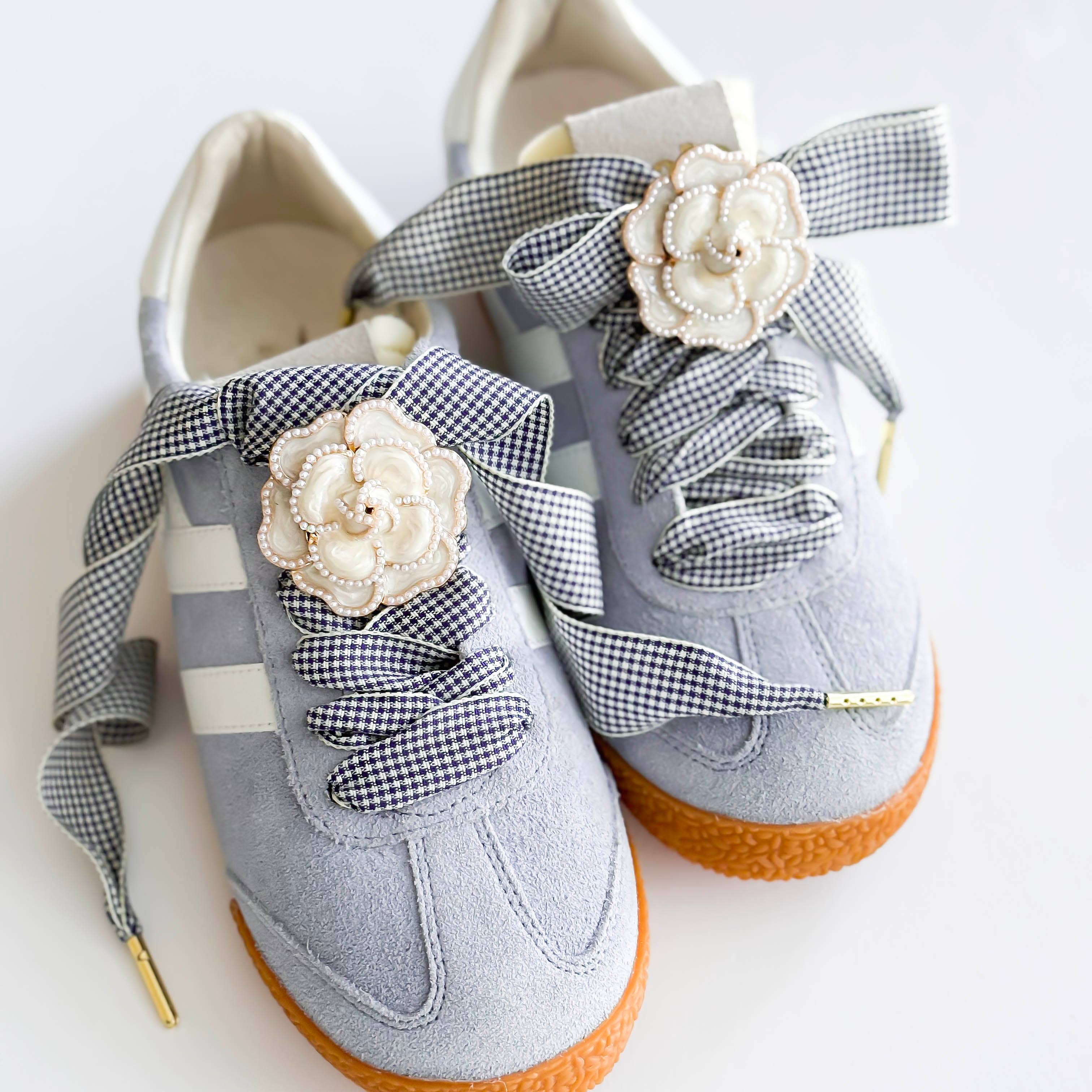 Gray shoes with decorative ribbons and flowers on a white background