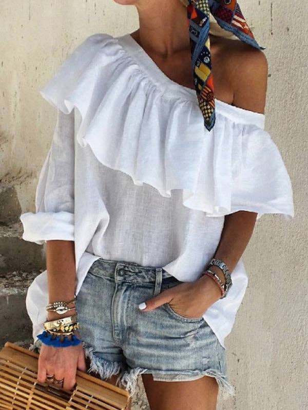 Woman wearing a white off-shoulder top and denim shorts with a colorful scarf on her head.