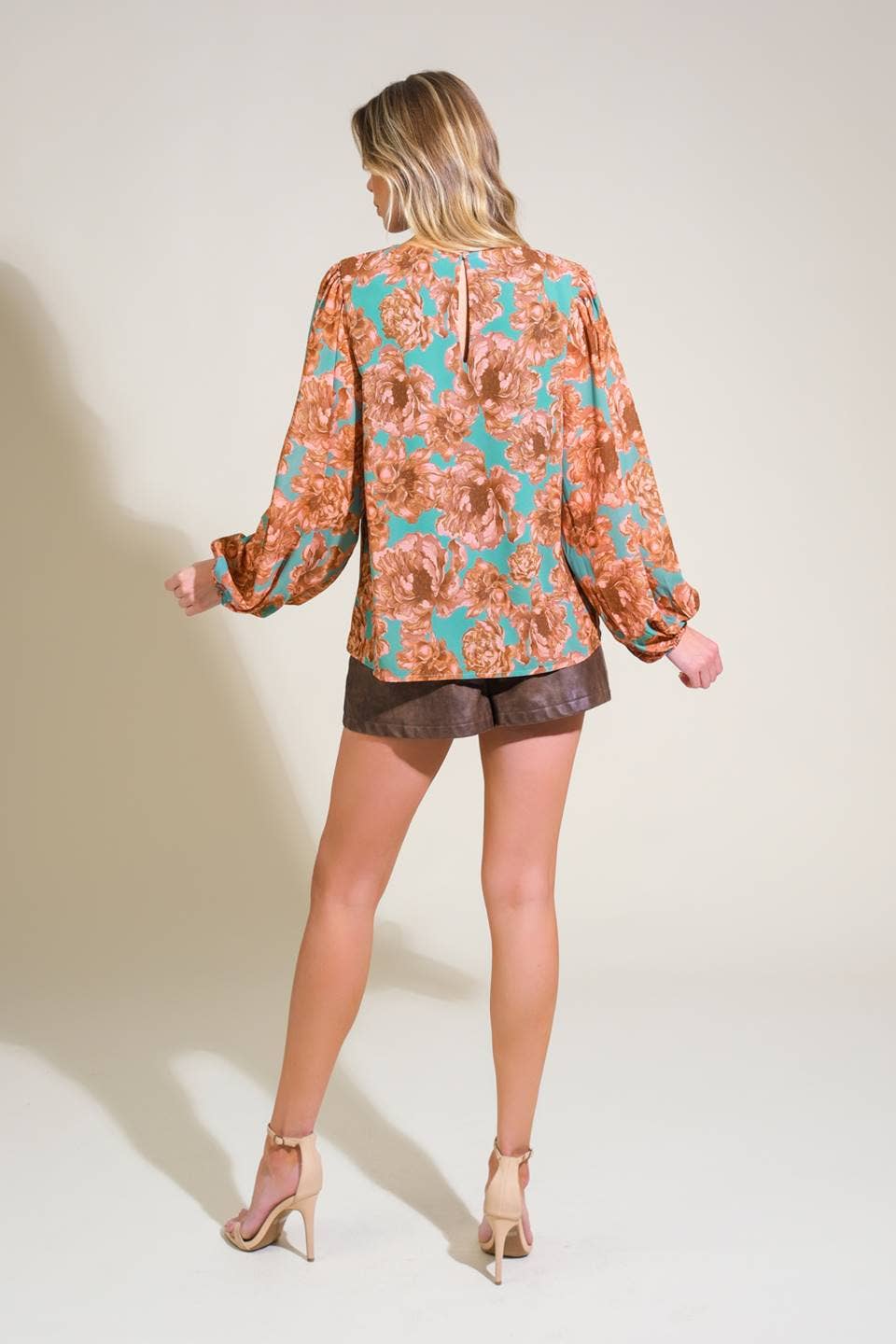 Woman wearing a patterned blouse and shorts on a plain background