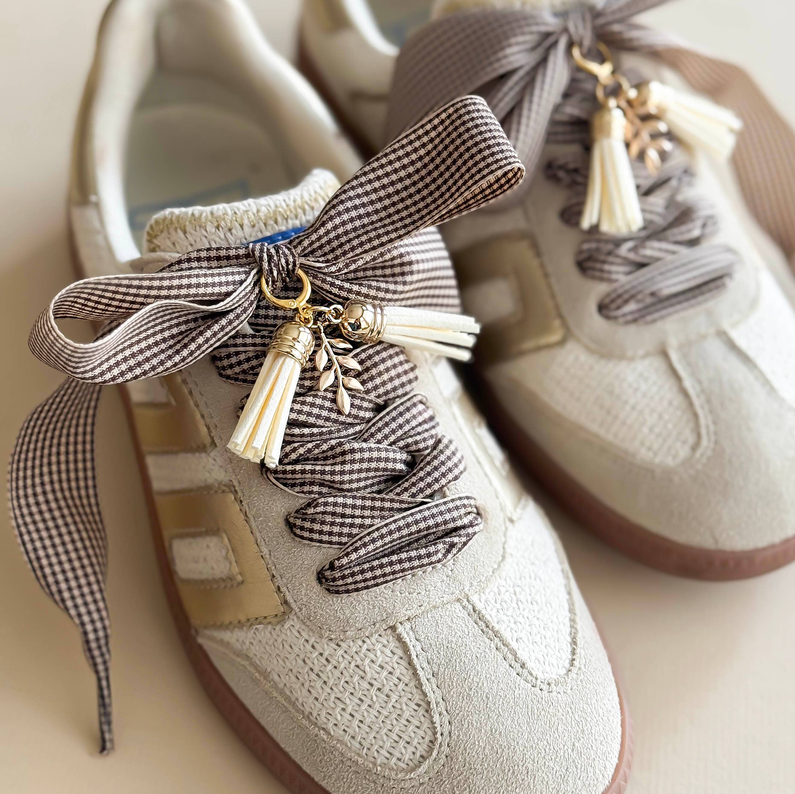 Beige sneakers with decorative ribbons and tassels on a light background
