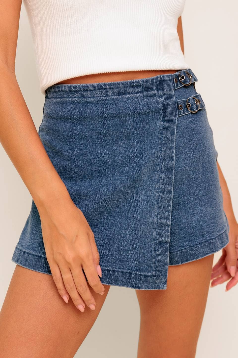 Person wearing a blue denim skirt on a plain background