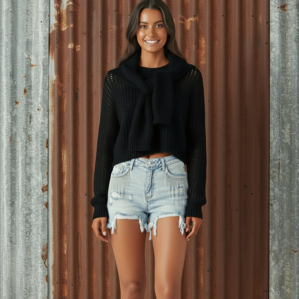 Person wearing a black crop top and light blue denim shorts on a white background