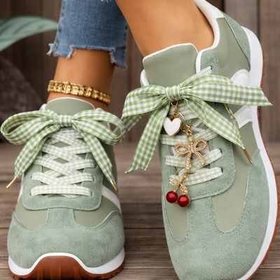 Green sneakers with decorative bows and charms on a wooden floor