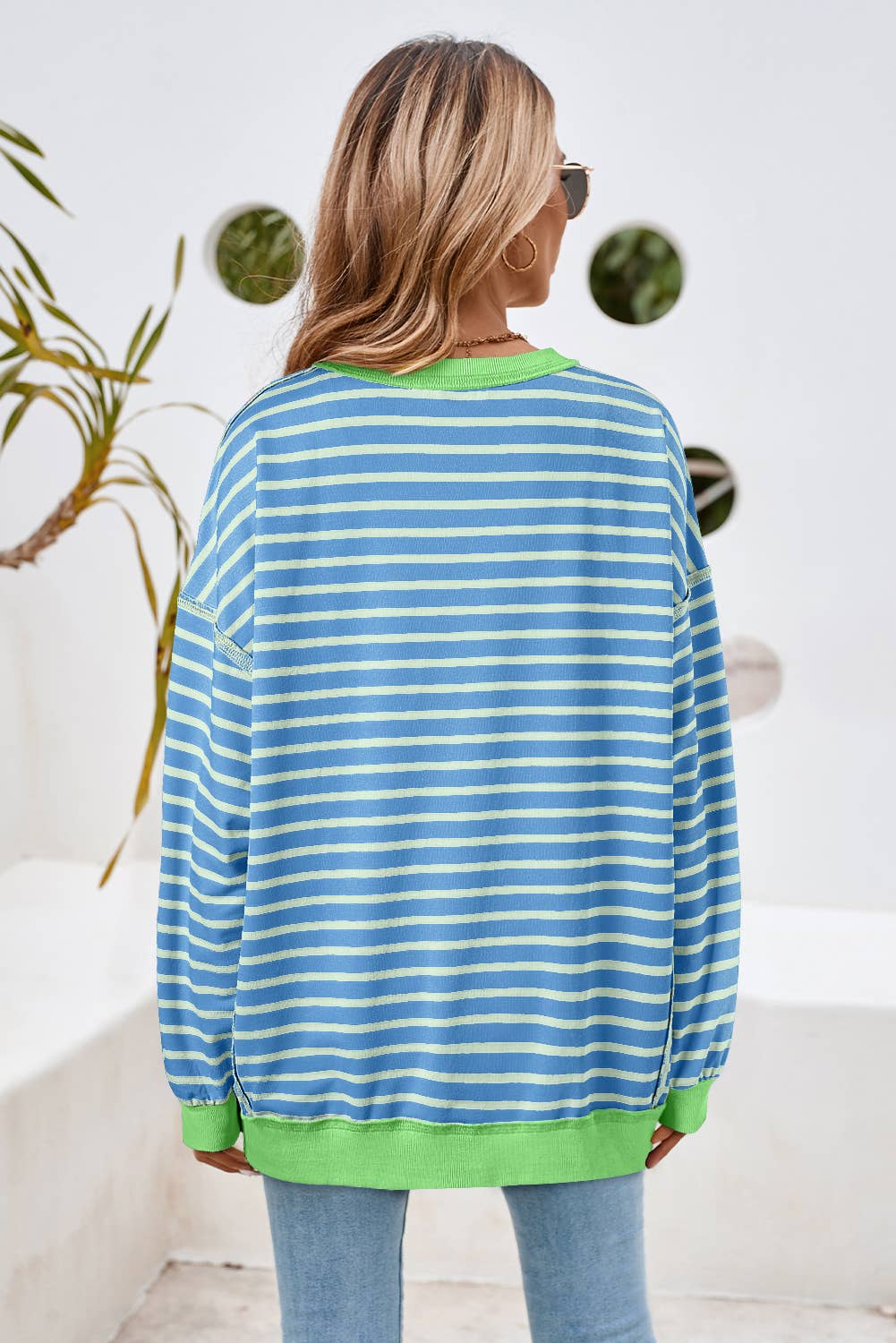 Person wearing a blue and green striped sweater with a white background