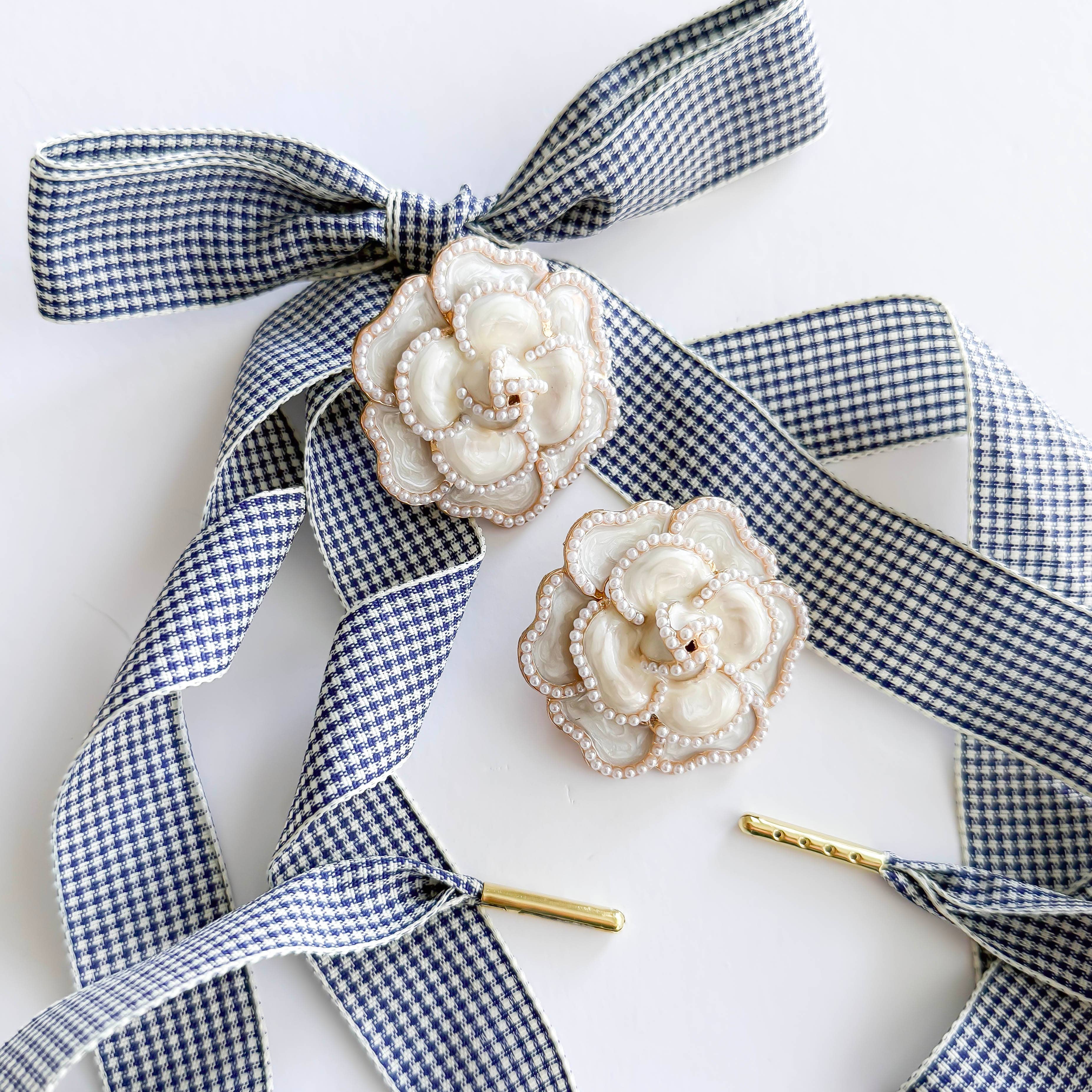 Decorative flower pins with blue gingham ribbons on a white background