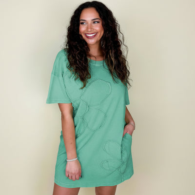 Woman wearing a green dress with floral patterns on a beige background