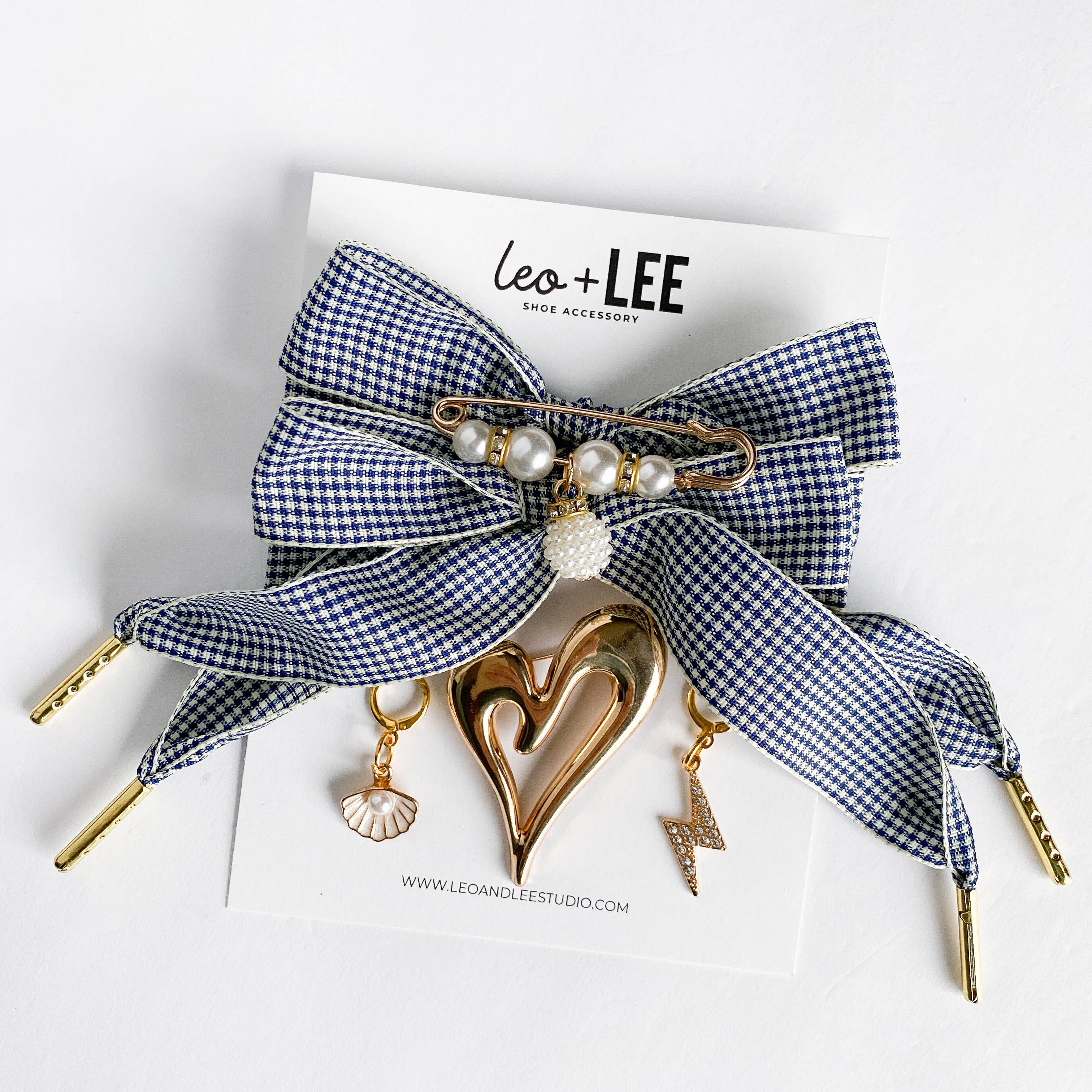Blue and white checkered bow hair accessory with gold elements on a white background with 'Leo + Lee' branding.