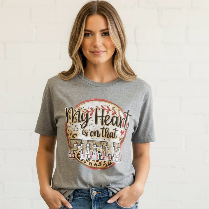 T-shirt with 'My Heart is on that Field' design, paired with jeans and sneakers on a wooden surface.