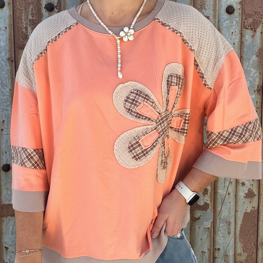 Person wearing an orange and brown top with a butterfly design against a white background
