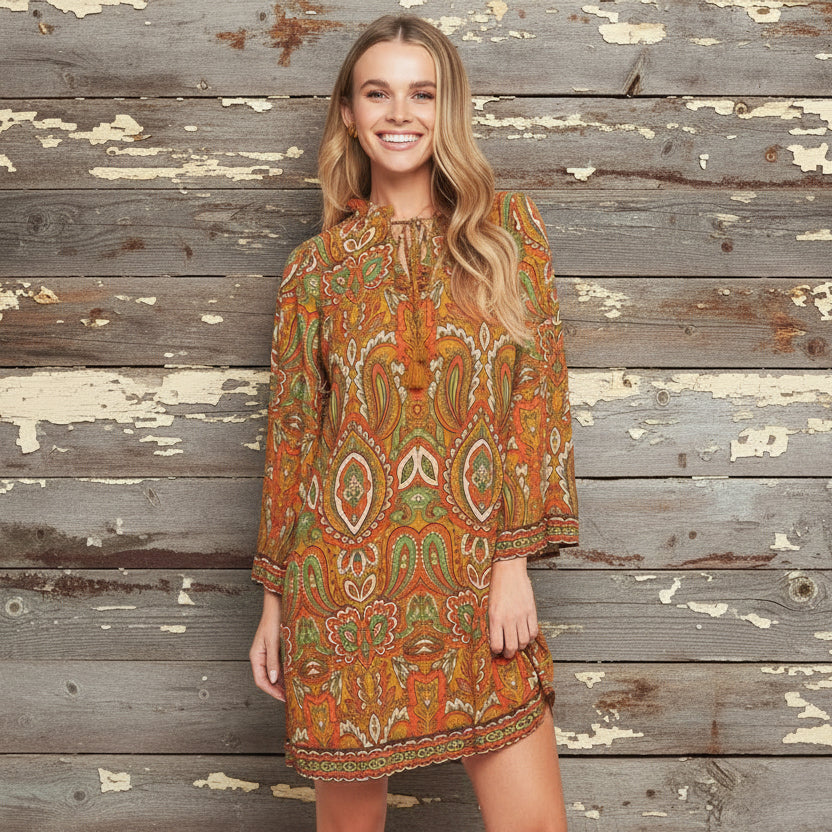 Woman wearing a patterned dress with beige boots on a plain background
