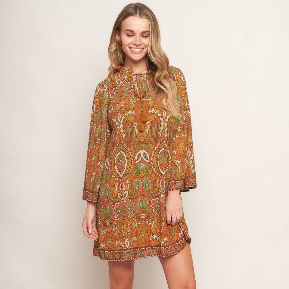 Woman wearing a patterned dress with beige boots on a plain background