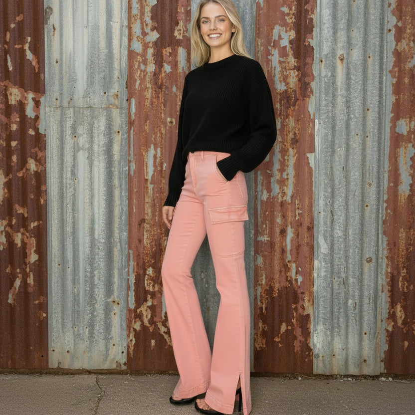 Woman wearing a black crop top and pink flared jeans on a white background