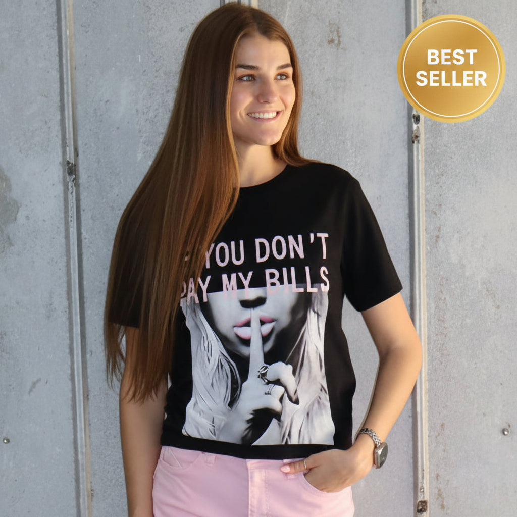 Person wearing a black t-shirt with text and pink shorts standing on a concrete floor.