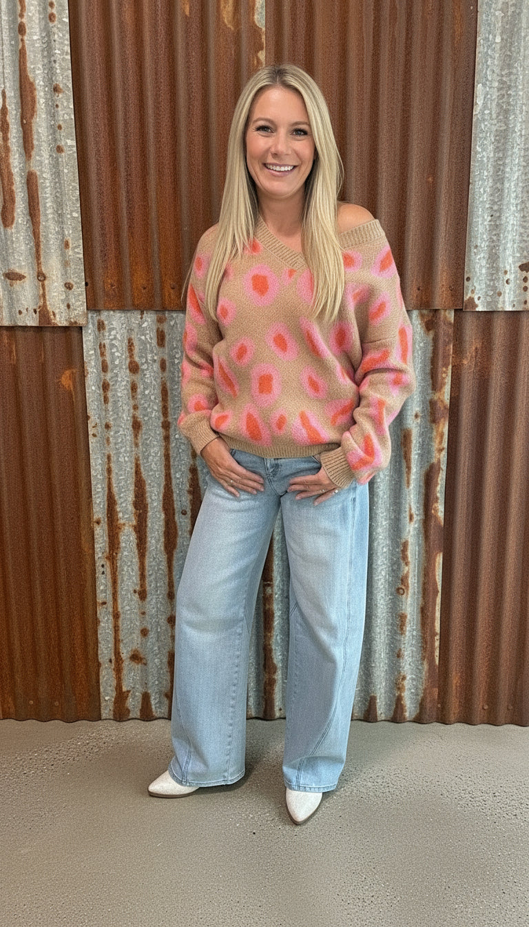 Woman wearing a colorful sweater and jeans standing in a room with a chalkboard wall.