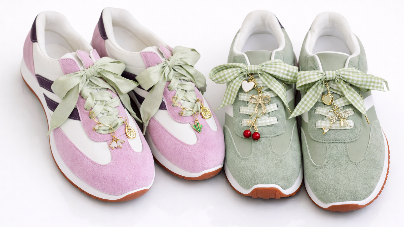 Pair of pink and green sneakers with decorative bows and charms on a white background